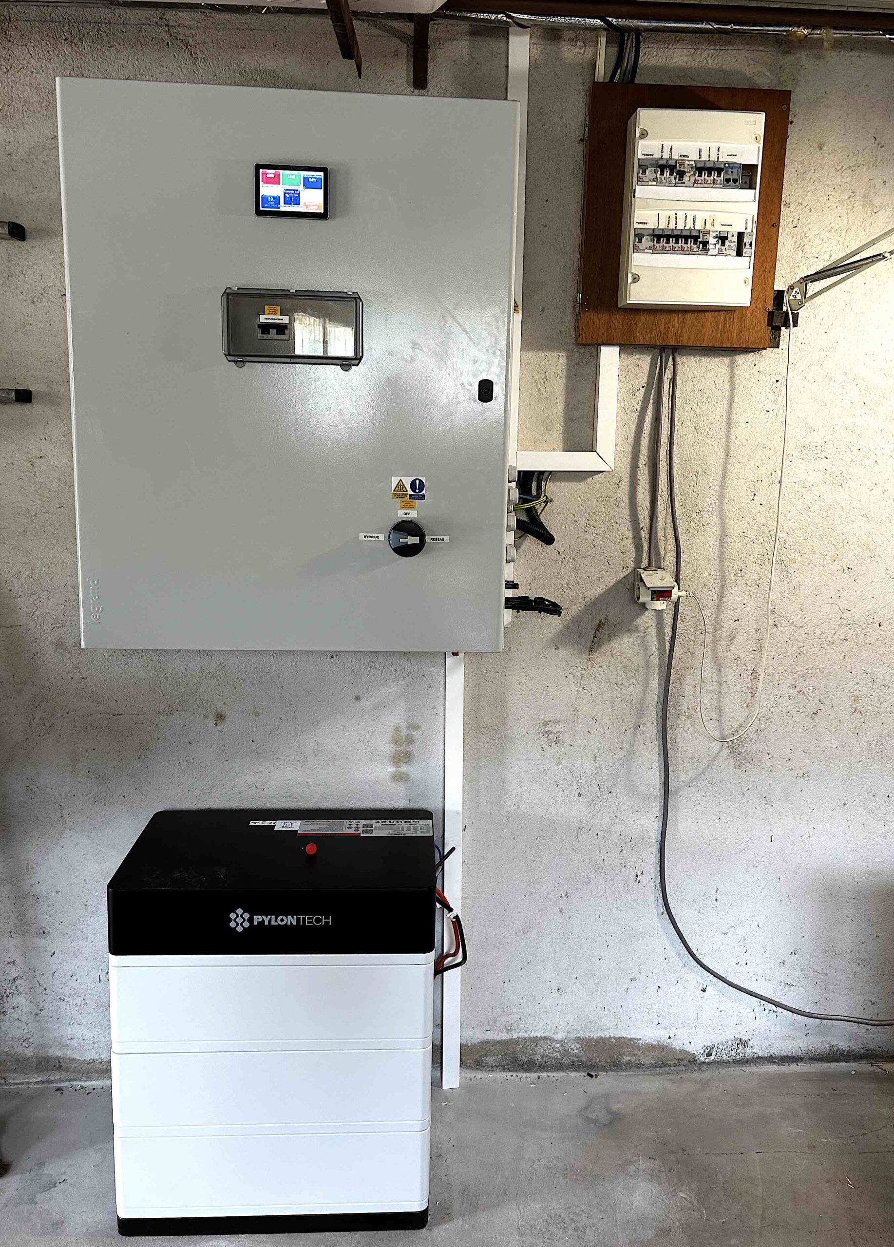 Armoire électrique grise avec écran de contrôle et batterie Pylontech installées dans un garage