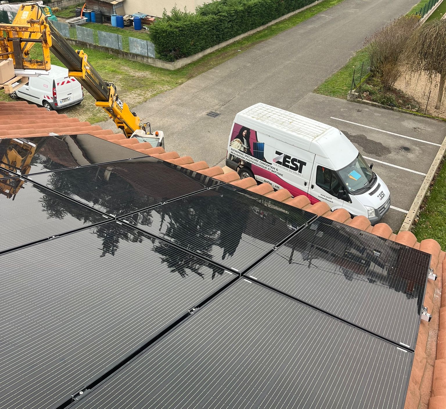 Chantier d'installation de panneaux solaires sur toiture avec camion ZEST et nacelle élévatrice