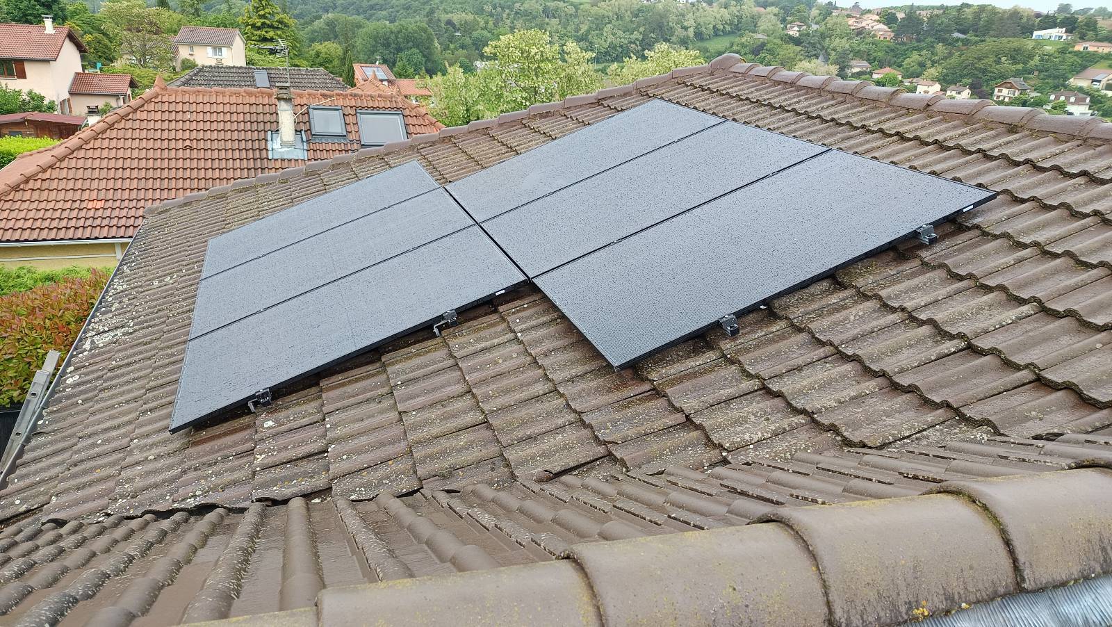 Panneaux solaires installés sur toiture en tuiles avec vue sur quartier résidentiel