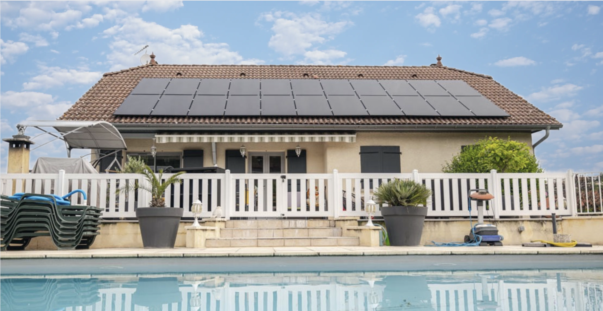 Maison avec panneaux solaires sur toiture vue depuis la piscine