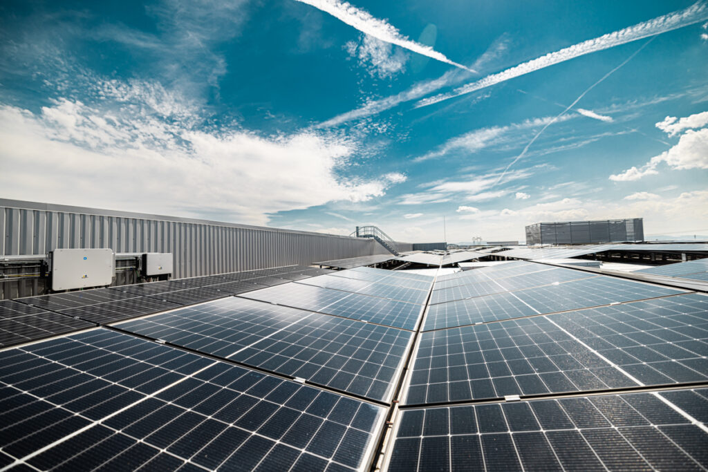 Installation photovoltaïque sur toiture industrielle avec onduleurs et ciel bleu