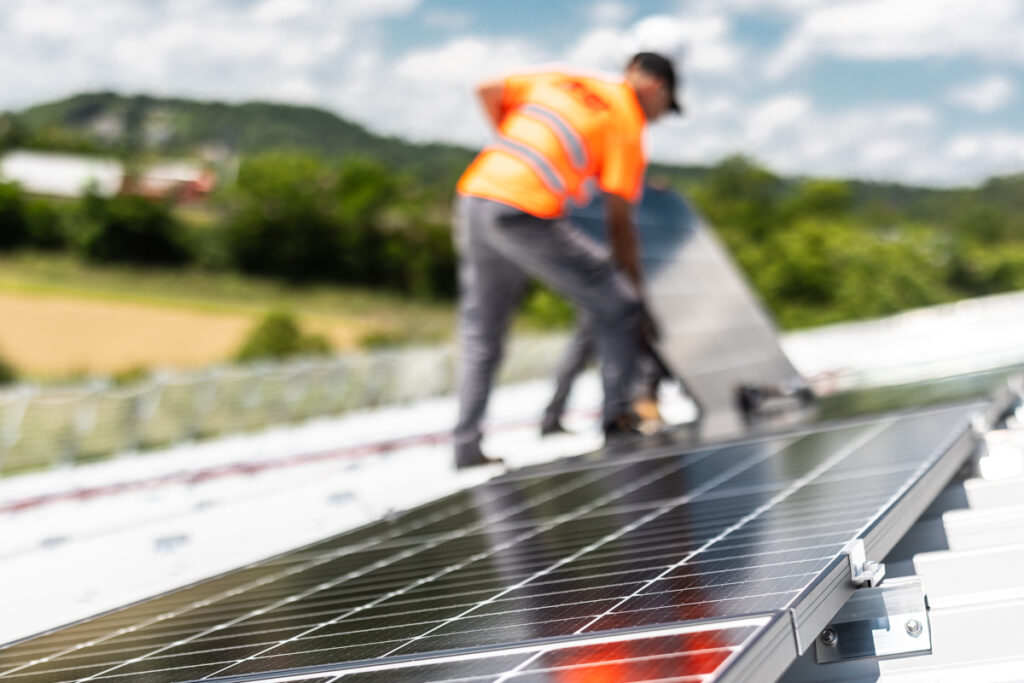 Technicien Zest en gilet de sécurité installant des panneaux solaires sur une toiture