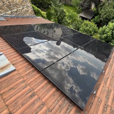 Panneaux solaires installés sur un toit de tuiles avec jardin verdoyant en arrière-plan