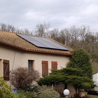 Maison avec panneaux solaires sur toit en tuiles et volets en bois dans un environnement boisé