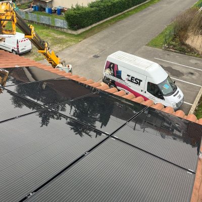 Chantier d'installation de panneaux solaires sur toiture avec camion ZEST et nacelle élévatrice