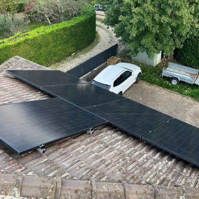 Panneaux solaires installés sur toiture avec voiture blanche garée dans la cour