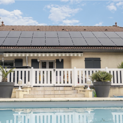 Maison avec panneaux solaires sur toiture vue depuis la piscine