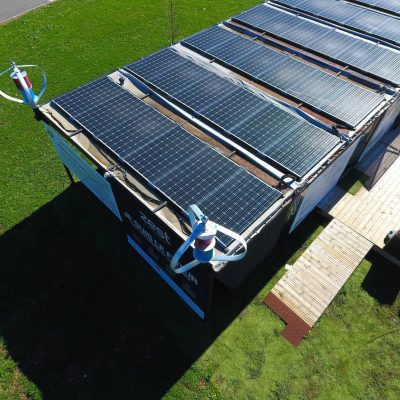 Vue aérienne de maison avec panneaux solaires et éolienne domestique dans le jardin